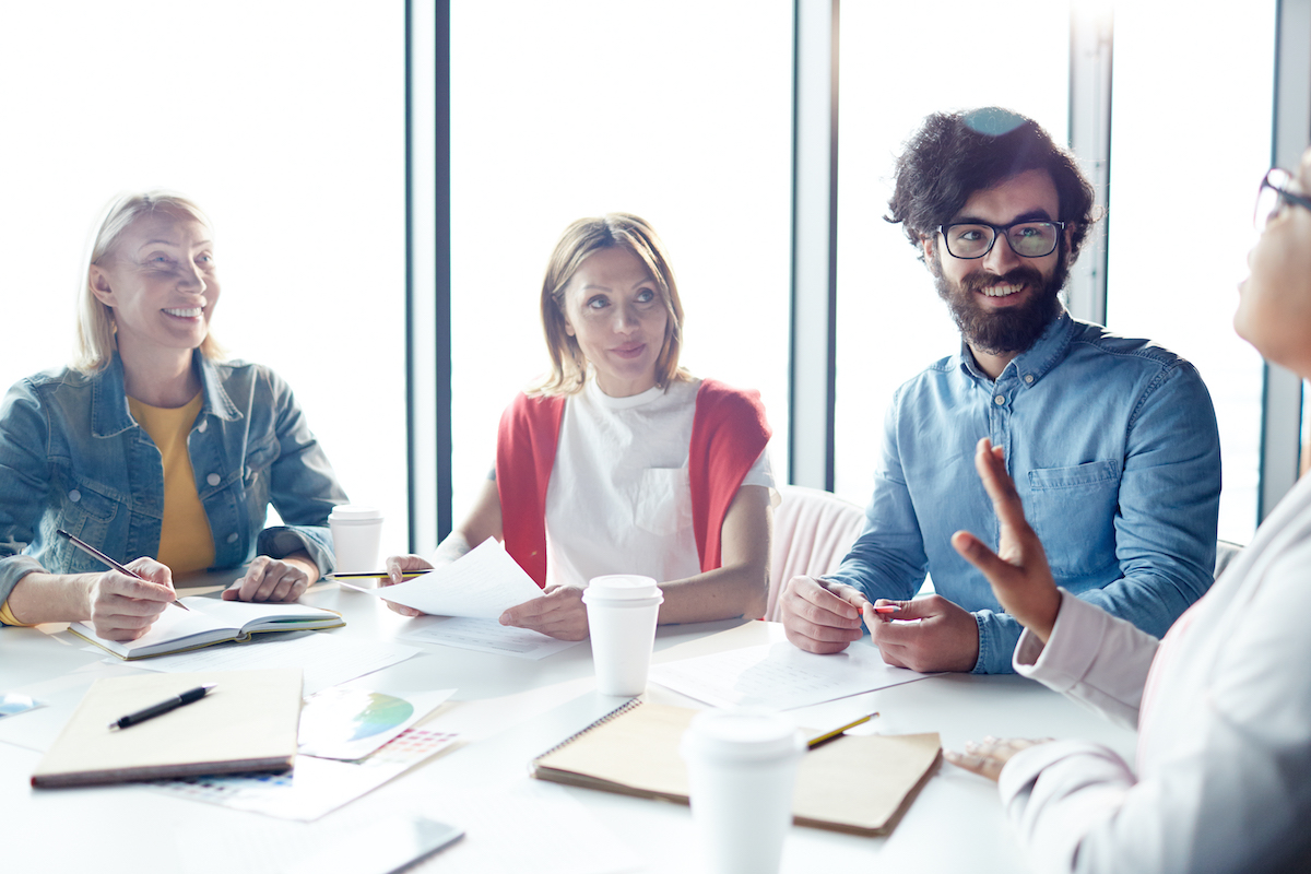 Drop default tagline image of four coworkers around a table